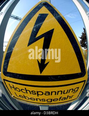 (Dpa) - Il mirroring di un segno di pericolo dicendo "Hochspannung - Lebensgefahr' (alta tensione - pericolo di vita) mette in guardia contro l'alta tensione di una stazione del trasformatore del gruppo Energie Baden-Wuerttemberg AG (EnBW) di Karlsruhe in Germania, 30 settembre 2003. Secondo EnBW nel consiglio di fabbrica 3.700 posti di lavoro Foto Stock