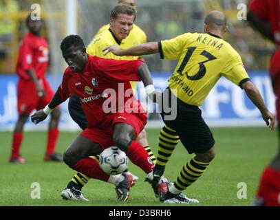 (Dpa) - Dortmund il defender Stefan Reuter (C) indietro e in avanti Giuseppe Reina (R) provare a prendere la palla fuori Friburgo il centrocampista Coulibaly dal Mali durante il Buundesliga gioco di calcio Borussia Dortmund contro SC Freiburg a Dortmund, Germania, il 27 settembre 2003. Dortmund ha vinto il gioco 1-0 un Foto Stock