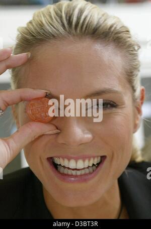 (Dpa) - Tedesco top model Heidi Klum detiene un "Heidi Klum frutta " di gomma nella parte anteriore del suo occhio, alla frutta Katjes gum e lakritz nella factory di Emmerich, Germania, 20 settembre 2003. Il modello ha aperto la nuova fabbrica e fu onorato con questa edizione speciale di 'monete' da Katjes. Dopo Katjes ha firmato un con Foto Stock