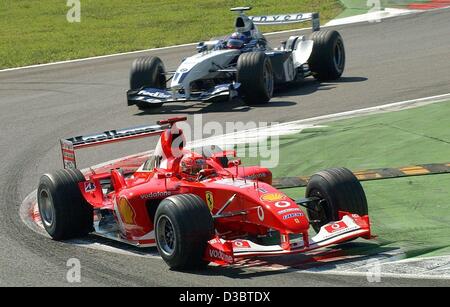 (Dpa) - Tedesco pilota di Formula Uno Michael Schumacher della Ferrari (anteriore) conduce davanti a colombiano Juan Pablo Montoya (BMW-Williams) poco dopo la partenza del Gran Premio d'Italia a Monza, 14 settembre 2003. Schumacher vince la gara e conduce la classifica generale con 82 punti, seguito da Monto Foto Stock