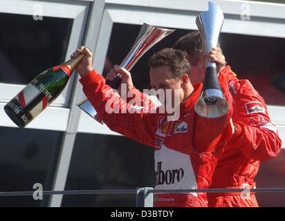 (Dpa) - Tedesco pilota di Formula Uno Michael Schumacher della Ferrari (R) e direttore della Ferrari Ross Brawn (coperto) allietare e wave i loro trofei dopo Schumacher ha vinto il Gran Premio d'Italia a Monza, 14 settembre 2003. Schumacher porta ora in classifica generale con 82 punti. Foto Stock