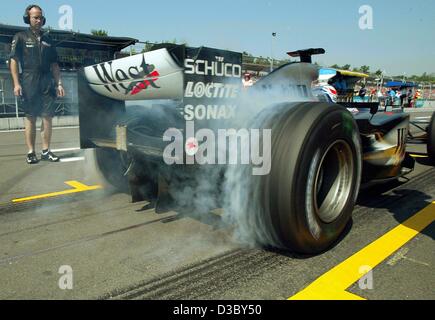 (Dpa) - Finlandese pilota di Formula Uno Kimi Raeikkoenen della McLaren Mercedes è spento in una nuvola di fumo come egli inizia dalla fossa durante la prima formazione gratuita su Hockenheim Anello pista di gara di Hockenheim, in Germania, 1 agosto 2003. La dodicesima marcia di campionati del mondo, il Gran Premio di Germania, Foto Stock