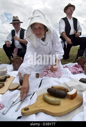 (Dpa) - gli agricoltori rivestita in abiti tradizionali hanno una pausa dal lavoro e mangiare durante il tradizionale 'Vergodendeel', la celebrazione della fine del raccolto su un campo in un museo a cielo aperto in Diesdorf nella regione di Altmark, Germania orientale, 27 luglio 2003. Come una tradizione secolare, il Vergodende Foto Stock