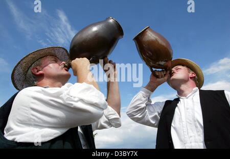 (Dpa) - Reinhard Pankonien (L) e Alf Elfert rivestita in abiti tradizionali hanno una pausa dal lavoro e di bere succo di lampone da brocche durante il tradizionale 'Vergodendeel', la celebrazione della fine del raccolto su un campo in un museo a cielo aperto in Diesdorf nella regione di Altmark, Germania orientale Foto Stock