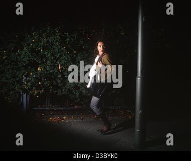 (Dpa) file - Il simbolico foto mostra una donna sola a piedi giù per una strada di notte e spaventati da una grande ombra (non datato, recenti foto). Foto Stock