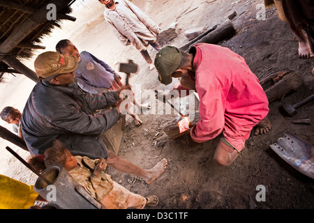 Madagascar Ranomafana, la lavorazione del ferro villaggio, uomo foro di punzonatura in rosso metallo caldo Foto Stock