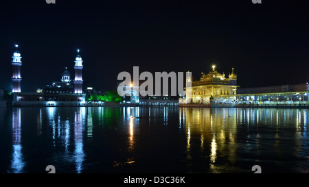 Il Tempio d'oro e minareti incandescente nella notte con il suo riflesso nella piscina sacra. Foto Stock