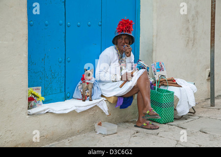 Licenza modello di strada in posa per i turisti come colorata donna cubana enorme per fumatori di sigari Avana e vestito cat in Old Havana, Cuba Foto Stock