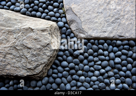 La piccola roccia fluviale, rotonda, perfettamente sagomata e grigio-blu contrasta con le grandi pietre piatte del design giapponese del percorso del giardino in Giappone. Foto Stock