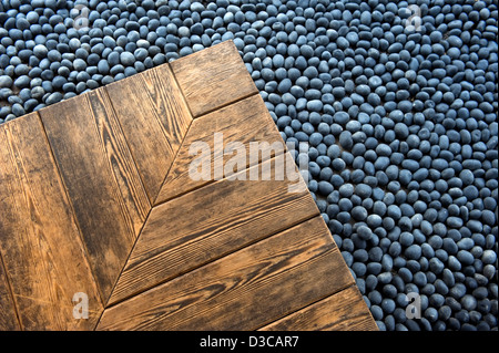 Angolo di caldo legno sgranate terrazza veranda contrasta con lo sfondo della rotonda liscia blue river rock nel giardino giapponese dettaglio. Foto Stock