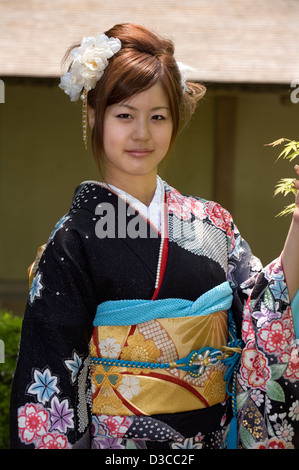 Carino, 20-qualcosa ragazza giapponese indossando il tradizionale furisode lungo il manicotto a kimono con molla design floreale pone a Fukui, Giappone Foto Stock