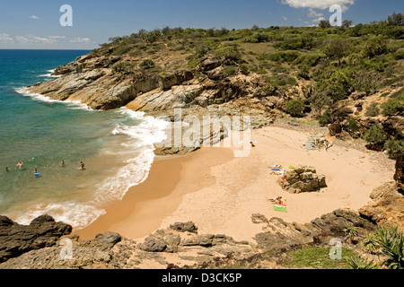 La gente di nuoto e altri sulla spiaggia nella pittoresca baia isolata circondata da rocce vicino alla città di 1770 Queensland Australia Foto Stock