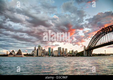 Colorato arancione tramonto oltre la Sydney Opera House guardando indietro al CBD di Sydney Circular Quay Australia Foto Stock