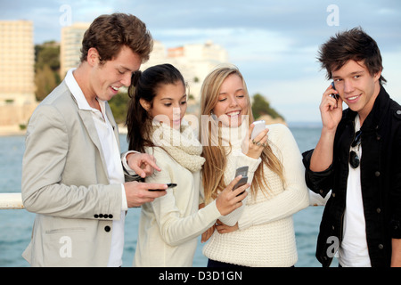 Teens parlare o scrivere messaggi sui telefoni cellulari. Foto Stock