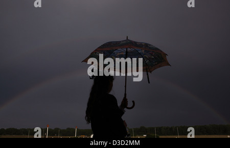 Hoppegarten, Germania, Silhouette, donna con ombrello in piedi di fronte a un arcobaleno Foto Stock