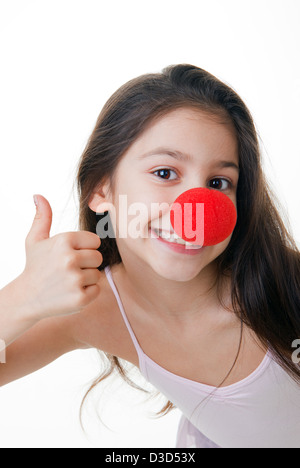 Bambino con red clown naso pollice in alto Foto Stock