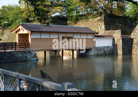A newly restored cover bridge crosses over a moat on the outside of the stone wall fortress at Fukui Castle in Fukui City, Japan Foto Stock