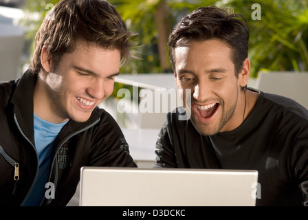 Due giovani uomini nella parte anteriore del computer portatile Foto Stock