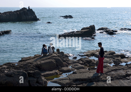 Pesca pescatore mentre i visitatori godere la vista del rocky, robusto Mare del Giappone costa in Tojinbo, Fukui, Giappone Foto Stock