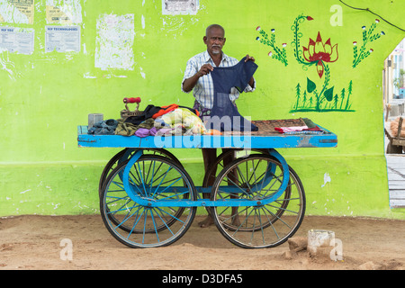 La tradizione indiana street servizio lavanderia man (dhobi) stiratura panni lavati su un carrello. Andhra Pradesh, India Foto Stock