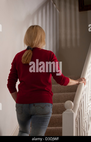 Vista posteriore di una bionda donna dai capelli da soli, passeggiate al piano di sopra di casa. Foto Stock