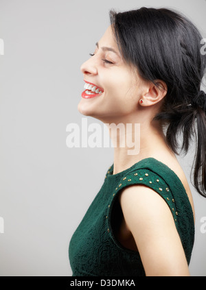 Ritratto di una giovane e bella donna che indossa un verde abito elegante su sfondo grigio. Foto Stock