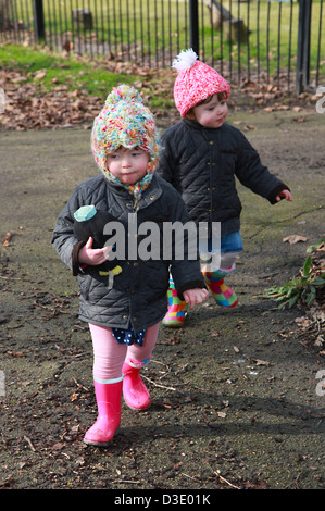 Il Toddler due gemelle a giocare nelle pozzanghere nel park REGNO UNITO Foto Stock