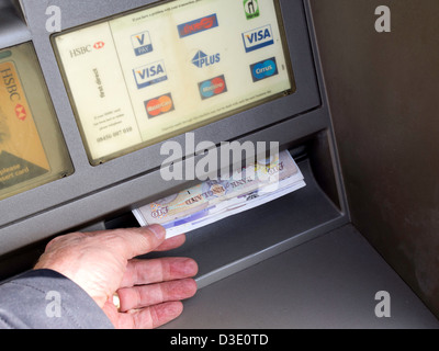 Una mano d'uomo prendendo £100 denaro erogato da una banca bancomat Foto Stock