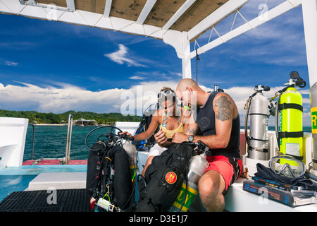 Due subacquei revisione piano di immersione e controllare le attrezzature tecniche sulla barca prima di iniziare la tec dive. Roatan, Honduras Foto Stock