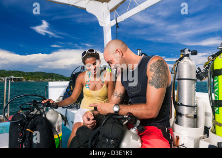 Due subacquei revisione piano di immersione e controllare le attrezzature tecniche sulla barca prima di iniziare la tec dive. Roatan, Honduras Foto Stock