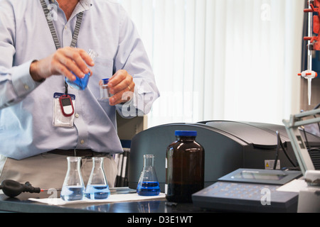 Ingegnere di lavoro con bottiglie di indigo soluzione con acqua ozonizzata in impianto di trattamento delle acque Foto Stock