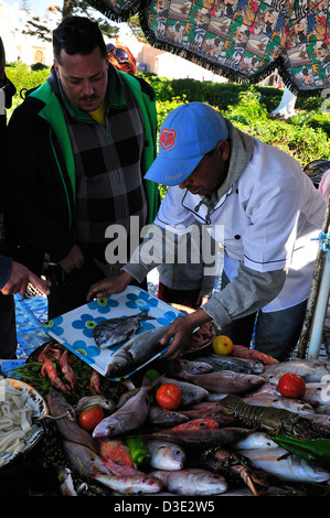 Pescivendoli con assortimento di pesci dal vicino porto di Essaouira , per grigliare nei ristoranti di pesce all'aperto a Essaouira, Marocco Foto Stock