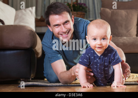 Padre giocando con suo figlio sul pavimento Foto Stock