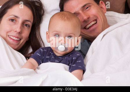 I genitori nel letto con il loro figlio che ha un succhietto Foto Stock