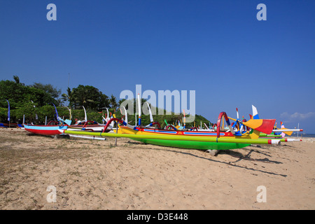 Vivacemente colorate barche da pesca, chiamato Jukungs, allineate sulla spiaggia di Sanur, Bali, Indonesia Foto Stock