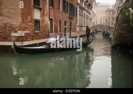 Un gondoliere porta i turisti per un giro in gondola durante una nevicata a Venezia, Italia. Foto Stock