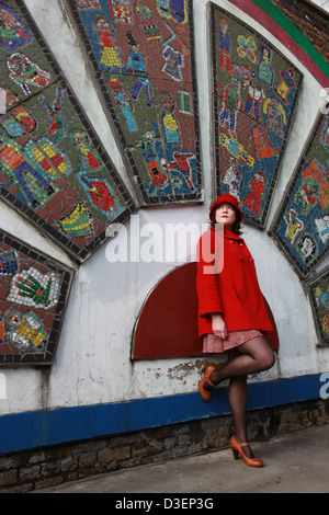 Signora In rosso in attesa di qualcuno in Brick Lane Foto Stock