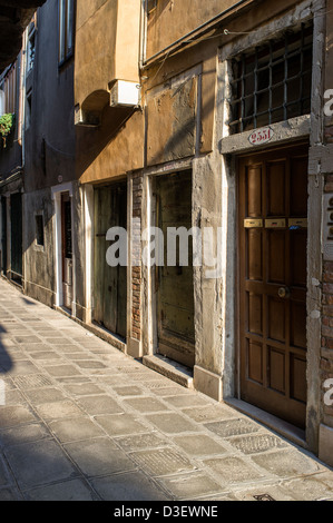 Sera La luce del sole in una stretta viuzza lastricata in Venezia Foto Stock