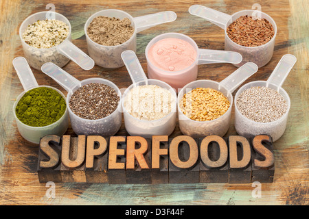 Superfoods word in rilievografia tipo di legno con palline di plastica di sementi sane e polveri Foto Stock