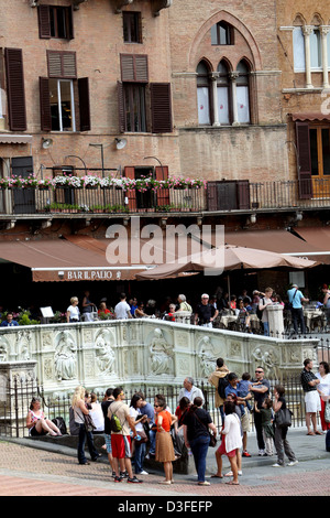 I turisti si sono riuniti intorno alla Fonte Gaia in Piazza del Campo a Siena Italia Foto Stock