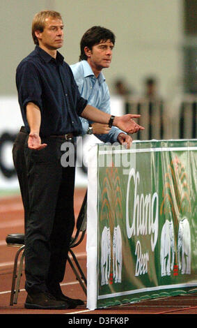 (Dpa) - Tedesco head coach Juergen Klinsmann (L) e il suo assistente Joachim Loew (R) guarda i loro giocatori sul campo durante l'amichevole internazionale tra la Tailandia e la Germania a Rajamangala National Stadium di Bangkok, Thailandia, 21 dicembre 2004. La Germania ha vinto con un punteggio finale di 5-1. Foto Stock