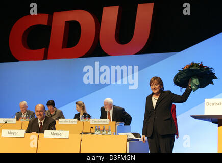 (Dpa) - Angela Merkel, presidentessa del cristiano democratico tedesco Unione (CDU), onde con un mazzo di fiori nella parte anteriore della CDU logo dopo essere rieletto durante la CDU del XVIII Congresso di partito a Duesseldorf in Germania, 6 dicembre 2004. Il leader della Germania opposizione cristiano-democratici, Angela Merkel, re-è stato eletto da una maggioranza schiacciante come leader del partito presso il convento Foto Stock