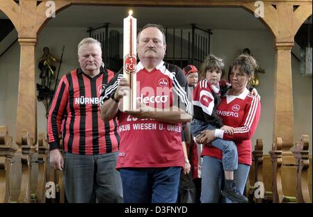 (Dpa) - Otto Scheer (anteriore), presidente del tifoso di calcio club di 1FC Norimberga tiene una candela in mano ed è seguita da una processione dei tifosi connazionali in una chiesa di Wiesen, Germania, 15 maggio 2003. I quindici membri del fan club acceso un cero nella speranza che Norimberga rimarrà in tedesco la premier league appena due giorni prima della fine della stagione. La sola possibilità per Nurembe Foto Stock