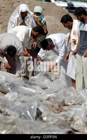 (Dpa) - uomini irachena cerca di sacchetti di plastica contenente le ossa e vestiti in una fossa comune nei pressi del villaggio di El Khatonia, 80 chilometri a sud di Bagdad, 14 maggio 2003. Gruppi di iracheni cercato attraverso migliaia di sacchetti di plastica contenenti i resti di soldati iracheni e alcuni civili che sono stati scoperti in una fossa comune. Tutte le vittime si crede siano stati uccisi da lealisti c Foto Stock