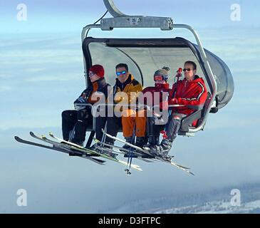 (Dpa) - Quattro gli appassionati di sci lo sguardo al paesaggio invernale al di sotto di esse mentre vengono trasportati da una sedia di sollevamento per la parte superiore del Fichtelberg montagna vicino a Oberwiesenthal, Germania, 11 febbraio 2003. Ideale inverno meteo - sole, neve polverosa, e temperature fresche - fornire questi sciatori e altri con ottime condizioni sulle piste da sci e piste per lo sci di fondo. Foto Stock