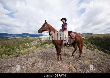 Cowgirl wrangler a cavallo a pecore rock, Montana, USA Foto Stock