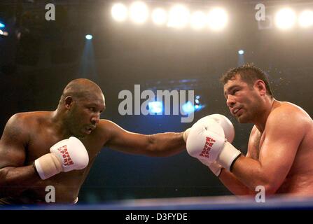 (Dpa) - Turco boxe pro Sinan Samil Sam (R), che vive ad Amburgo, tenta di bloccare un punzone dal suo avversario, l'Inghilterra del Julius Francesco, durante la loro lotta pesante a Schwerin, Germania, 26 aprile 2003. Samil Sam ha vinto la lotta da knockout nel settimo round e difende il suo Campionato Europeo titolo nel pesante. Foto Stock