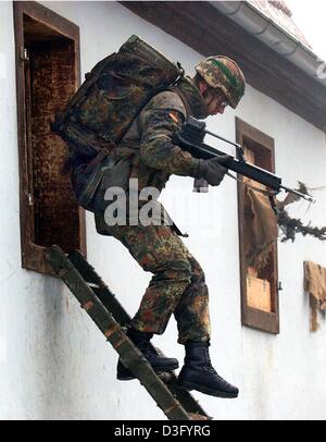 (Dpa) - un soldato della scuola di fanteria delle forze armate tedesche si arrampica fuori attraverso una finestra durante un esercizio nel villaggio disabitato 'Bonnland' a Hammelburg, Germania, il 3 febbraio 2003. "Bonnland' è un villaggio di sgomberato e edifici vuoti utilizzata come scenario di esercitazioni militari. Il 100-anno-vecchio case non hanno i vetri e non mobili, che li rende un sito ideale per TH Foto Stock