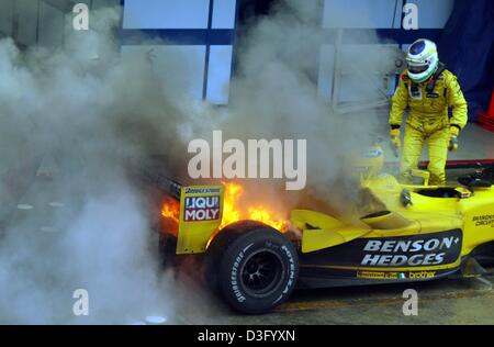 (Dpa) - italiano in Formula Uno pilota Giancarlo Fisichella écope dal cockpit del suo Giordania auto con il suo motore sul fuoco sulla pista di Interlagos in Sao Paulo, Brasile, 6 aprile 2003. Il bolide solo preso fuoco dopo la gara in cui Fisichella ha conquistato il secondo posto. A causa di forti precipitazioni la via è stata parzialmente allagata, causando diversi incidenti e dieci piloti di cadere fuori. T Foto Stock