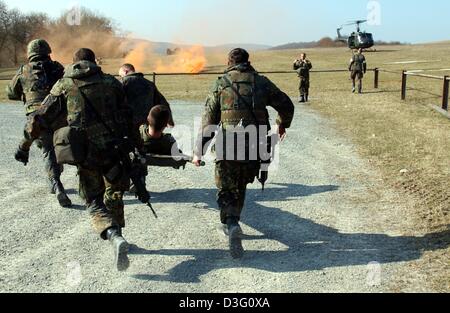 (Dpa) - i soldati dell'esercito tedesco corrono attraverso un campo verso un trinciatore in attesa con un soldato che simula il pregiudizio su una barella durante un campo exercsise nell'area formazione a Hammelburg, Germania, 20 marzo 2003. I soldati si preparano per la loro distribuzione come parte della KFOR in Kosovo. Circa 450 soldati tedeschi partecipa a questo esercizio. Foto Stock